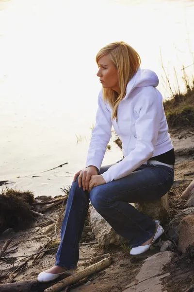 Kvinna sitter på rock på en strand — Stockfoto