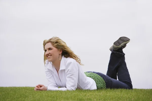 Een vrouw glimlachend en opleggen van gazon — Stockfoto