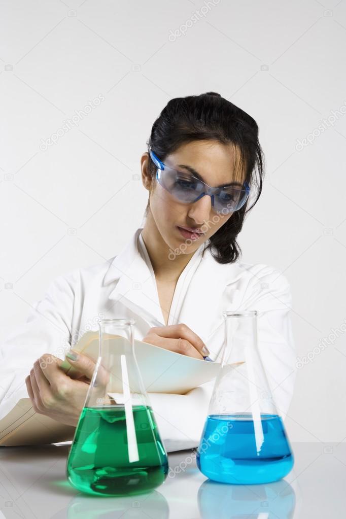 Woman Writing Results With Beakers