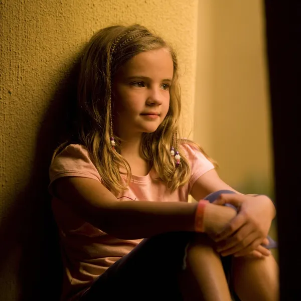 Mädchen sitzt an einer Wand — Stockfoto