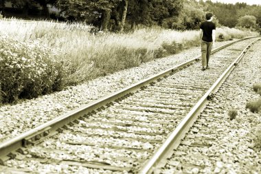 tren rayları üzerinde yürüyen adam