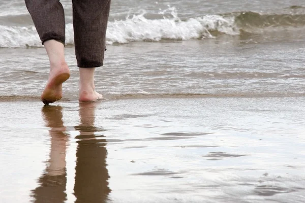 Person läuft barfuß am Strand — Stockfoto