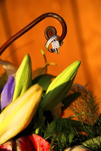 Eheringe auf Metallspirale über Blumenstrauß — Stockfoto