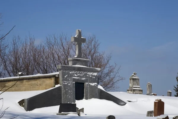 Grabsteine auf einem schneebedeckten Friedhof — Stockfoto