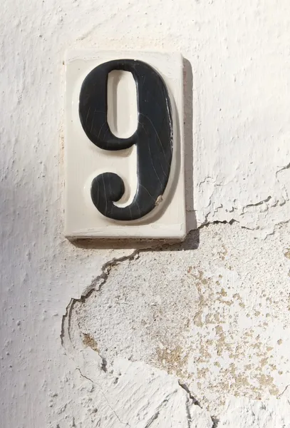 Keramische nummer negen op witgekalkte muur — Stockfoto