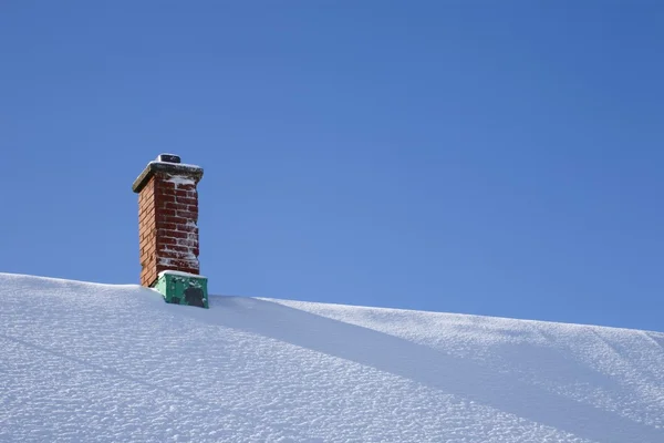 Schoorsteen op een besneeuwd dak — Stockfoto