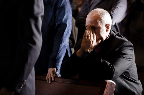 Man Praying In A Pew