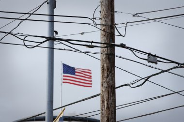telefon kabloları ve elektrik telleri arkasındaki Amerikan bayrağı