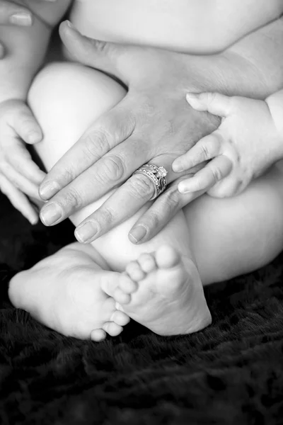 Mom's handen met baby's voeten en handen — Stockfoto