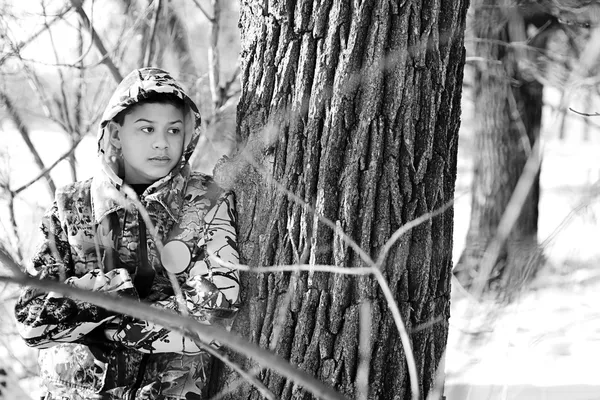 Adolescente menino caça em uma neve coberta de área arborizada — Fotografia de Stock
