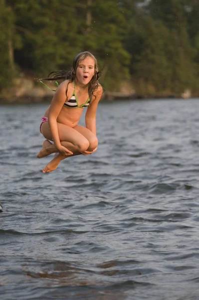 Jong meisje springen in lake — Stockfoto