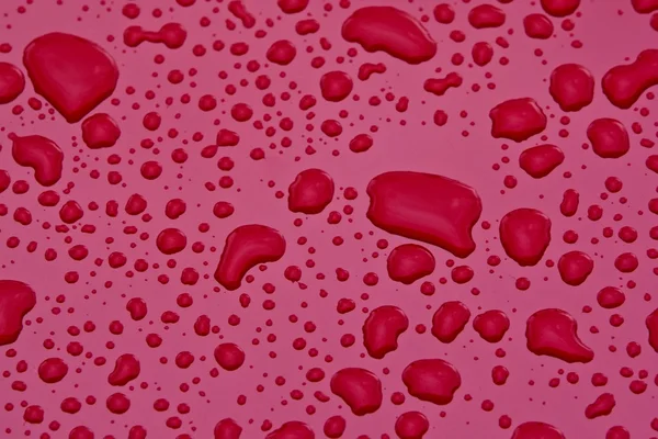 Gocce d'acqua sulla superficie rosa — Foto Stock