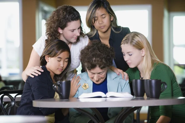 Groep van meisjes bidden voor senior vrouw — Stockfoto