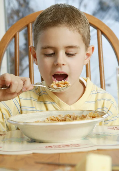 年轻的男孩，在早餐桌旁吃麦片 — 图库照片
