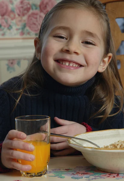 Menina com comida na mesa de café da manhã — Fotografia de Stock