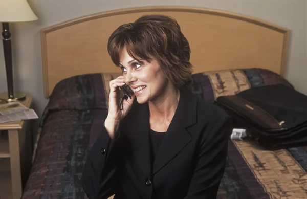 Donna d'affari che parla al telefono nella camera da letto dell'hotel — Foto Stock