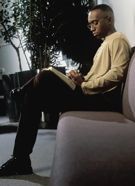 Homem leitura no sofá — Fotografia de Stock