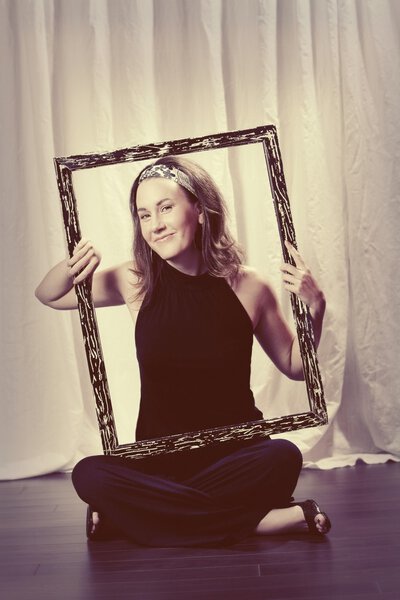 Woman Holding A Picture Frame Around Her Face And Torso