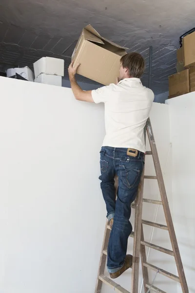 Uomo su un passo scala riordinare il soffitta — Foto Stock