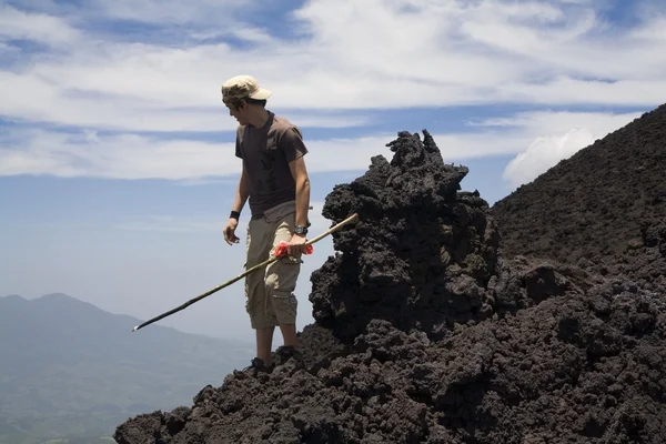 Hombre con un palo mirando hacia abajo una colina — Foto de Stock