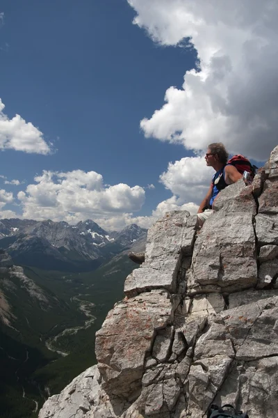 Man sitter på en bergstopp som njuter av utsikten — Stockfoto