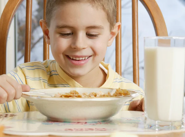 Menino comendo cereais na mesa de café da manhã — Fotografia de Stock