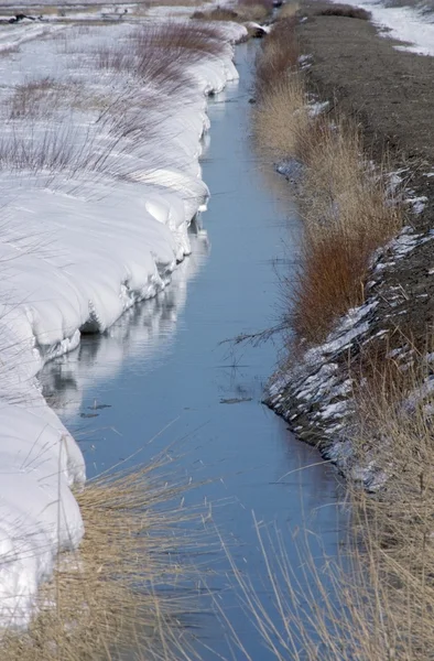Zanja de riego con deriva de nieve en un lado refleja cielo, Nuevo México, EE.UU. — Foto de Stock
