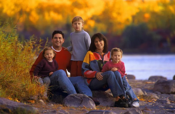 Familjen sitter på sten nära floden — Stockfoto