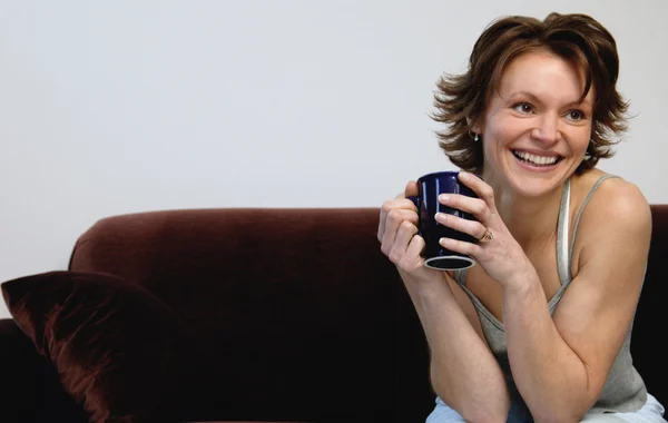 Mulher segurando café e sorrindo — Fotografia de Stock