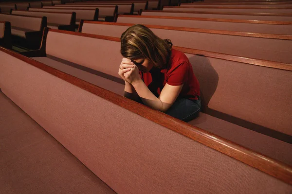 Žena se modlí v kostelní lavice — Stock fotografie