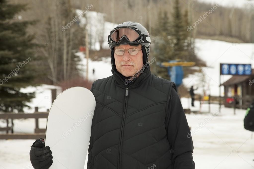 Man Holding A Snowboard Wearing A Helmet And Mask