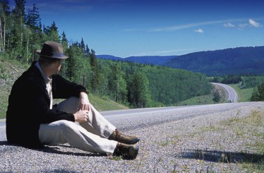 Hiker Sitting On Edge Of Country Road clipart