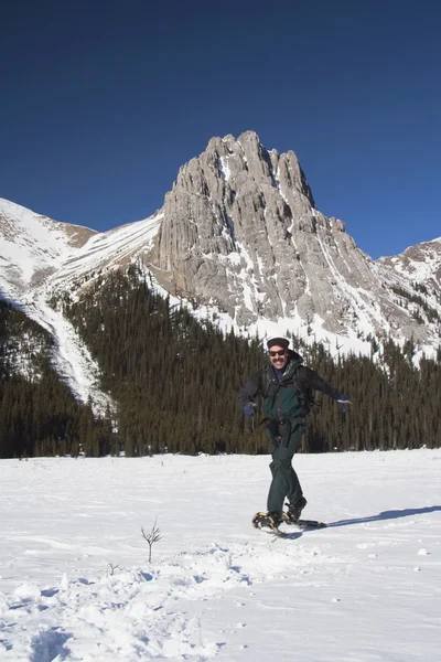 Homem caminhando em sapatos de neve nas montanhas — Fotografia de Stock