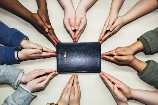 Mãos de oração apontando para uma Bíblia — Fotografia de Stock