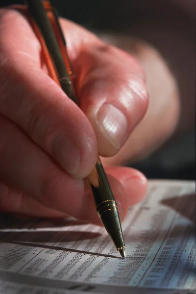 Close-up van man's hand en pen cirkelen investeringen in krant — Stockfoto