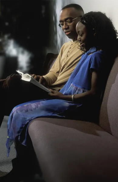 Férfi és a lány olvasókönyv kanapén — Stock Fotó