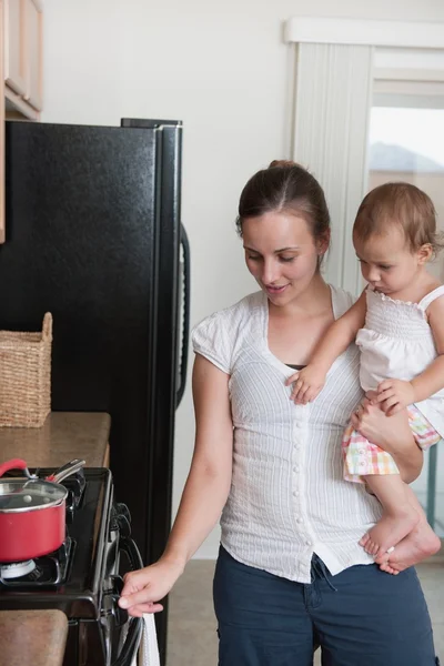 Moeder koken en een baby te houden — Stockfoto