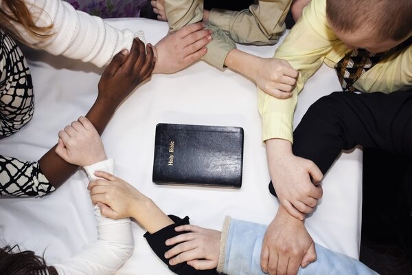 Group Of People Praying Around A Bible