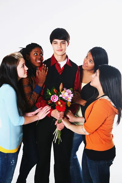 Chicas rodeando a un chico que sostiene flores —  Fotos de Stock