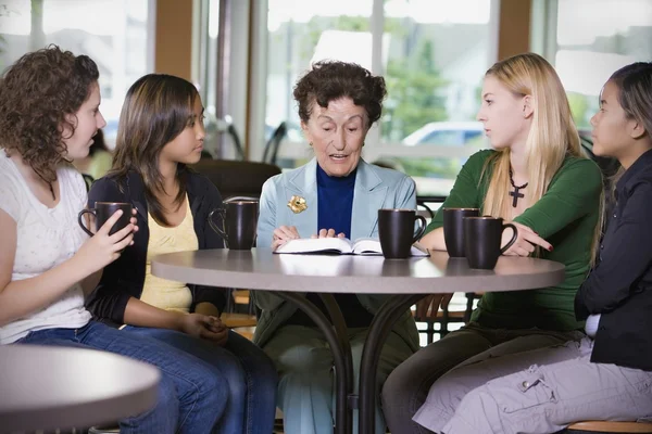 Группа девушек, слушающих пожилую женщину в ресторане — стоковое фото