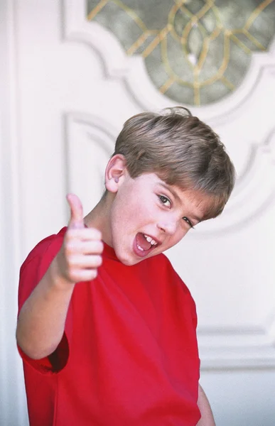 Boy With Thumbs-Up In Front Of Door — Stock Photo, Image