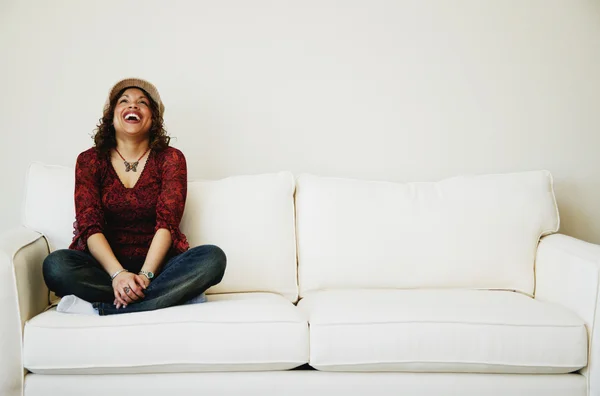 Rindo mulher sentada no sofá — Fotografia de Stock
