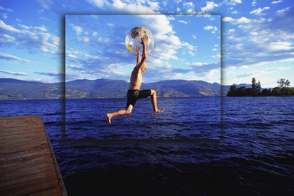 Pojke hoppa i sjön med Globe badboll — Stockfoto