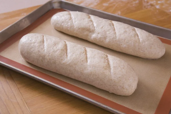 Două pâini nefierte de pâine pe o foaie de copt — Fotografie, imagine de stoc