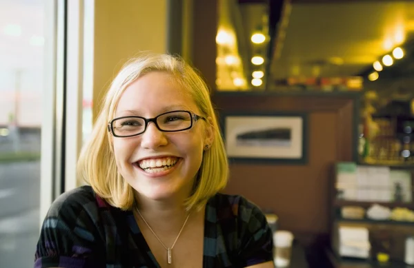 Mujer joven sonriendo en un café — Foto de Stock