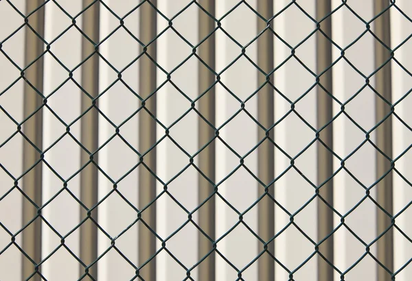 Ogrodzenie z drutu kolczastego i ściana za — Zdjęcie stockowe