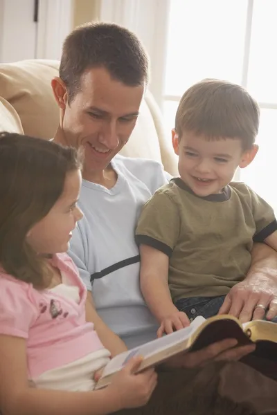 父亲给他年幼的儿子和女儿读圣经 》 — 图库照片