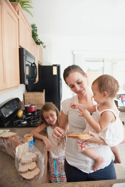 Moeder een sandwich maken voor haar meisjes — Stockfoto