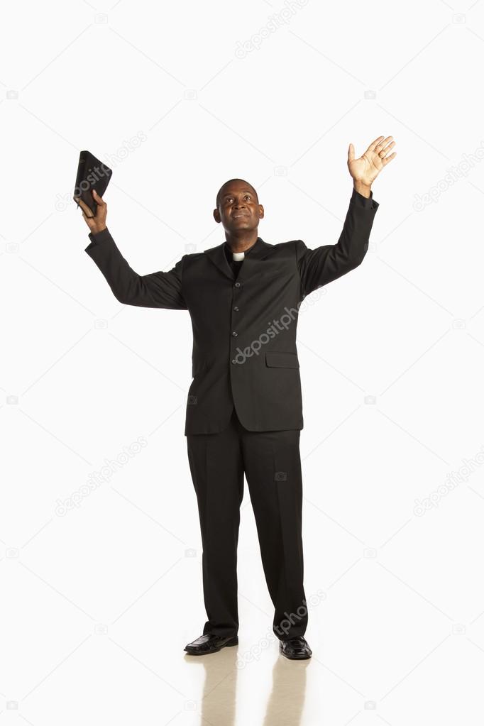Man Wearing A Clerical Collar And Holding His Bible Up