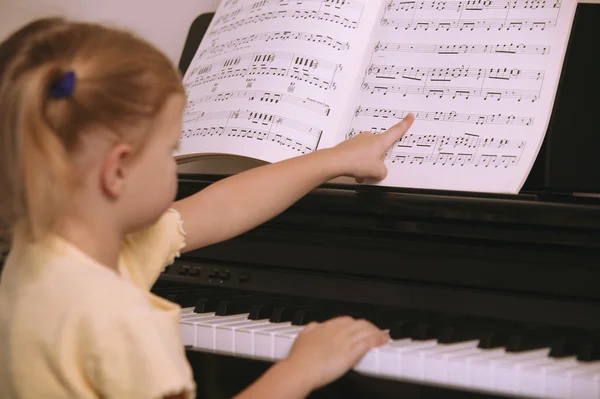 Criança aprende a tocar piano — Fotografia de Stock